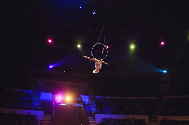 acrobata aéreo no ringue. Uma jovem executa os elementos acrobáticos no anel de ar
 - Foto, Imagem
