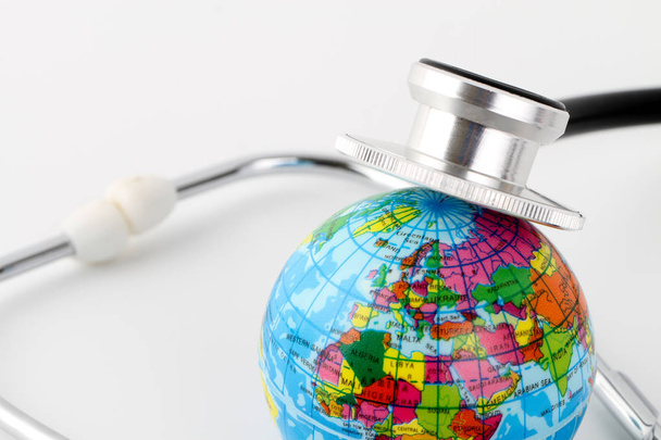studio shot of small earth planet globe toy and stethoscope - Foto, Imagem