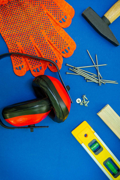 Herramientas profesionales para el carpintero y piezas de repuesto, auriculares sobre fondo azul
. - Foto, imagen