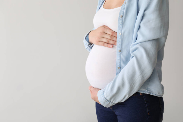 Hafif arka planda genç hamile bir kadın - Fotoğraf, Görsel