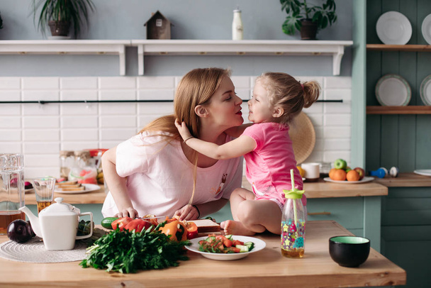 Mignonne mère et fille s'embrassant à la cuisine
 - Photo, image