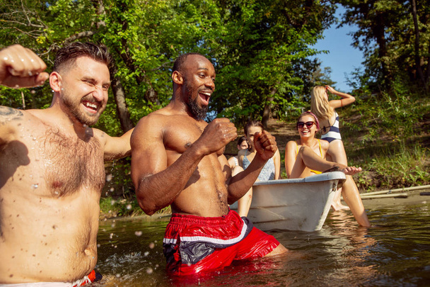 Happy group of friends having fun, laughting and swimming in river - Foto, imagen