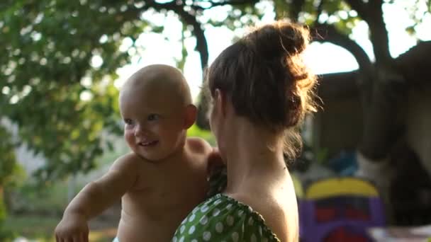 Zamknij portret matki i jednego roku życia dziecka w ogrodzie w wiosce na wakacjach. Urlop letni, dzień matki - Materiał filmowy, wideo