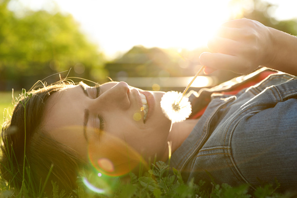 Young woman with dandelion in park on sunny day. Allergy free concept - Photo, Image