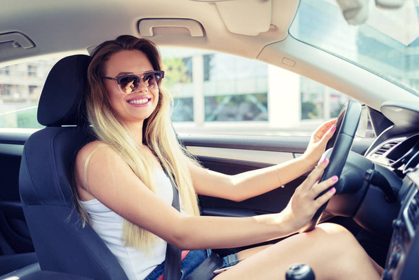 Gelukkig modieuze jonge vrouw rijden haar nieuwe auto-vrolijke zorgeloze rijke tiener meisje in nieuwe moderne voertuig dragen zonnebril genieten van City Ride in luxe gehuurde voertuig Modern Life concept - Foto, afbeelding