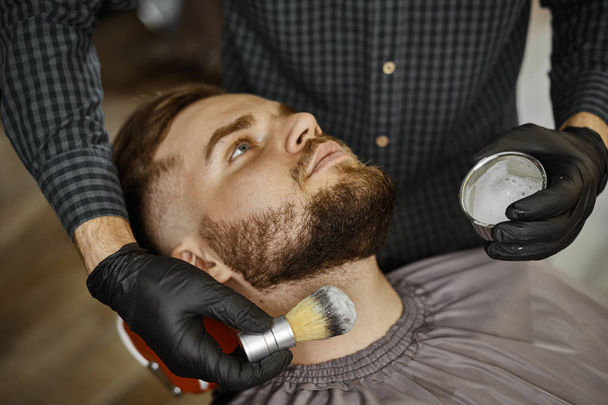um cara fazendo um corte de cabelo e estilo de uma barba
  - Foto, Imagem