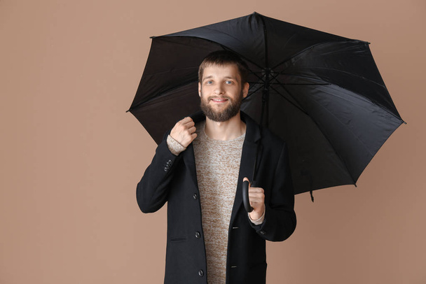 Handsome man with umbrella on color background - Foto, Imagem