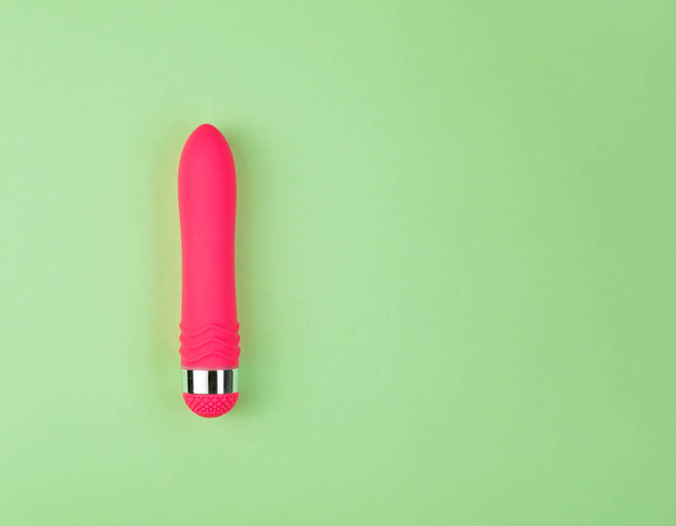 Beautiful evenly lit pink dildo on a plain green background with copy space. - Foto, immagini