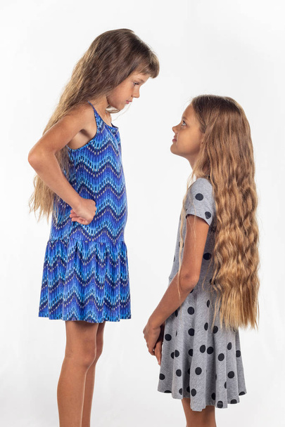 Two girls of different stature, one of them stood on a chair to be taller than the other - Photo, Image