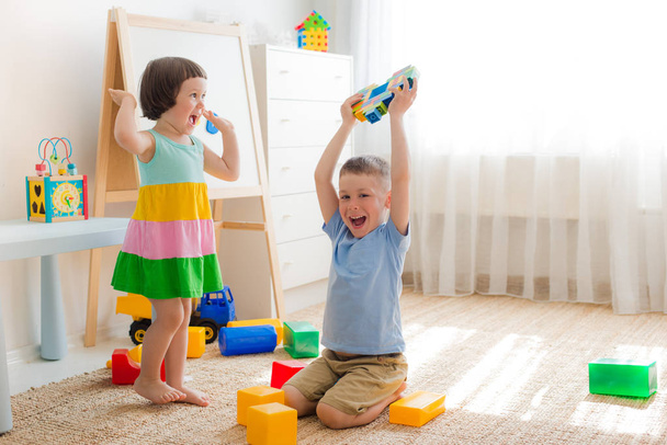 Niños felices juegan en la habitación en el suelo. Hermano y hermana juegan juntos. - Foto, Imagen