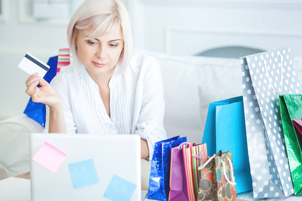 Érett nő csinál online vásárlás otthon a laptopon. Női hogy Internet-megrendelés. Midadult nő bevásárlótáskákkal. - Fotó, kép