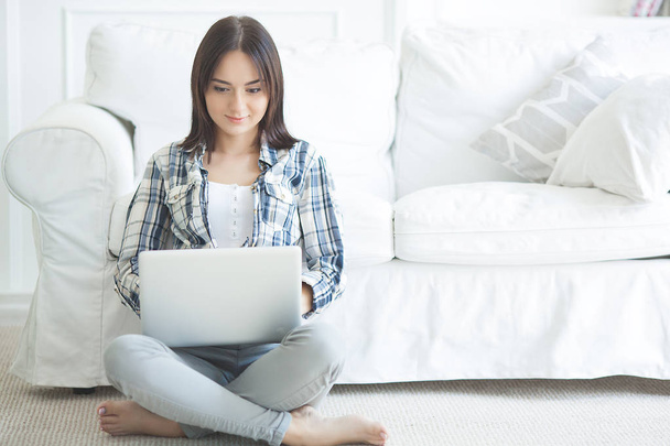 Atrakcyjna młoda kobieta pracuje na laptopie. Kobiece pisanie na PC. Młoda dama w domu z komputerem. - Zdjęcie, obraz