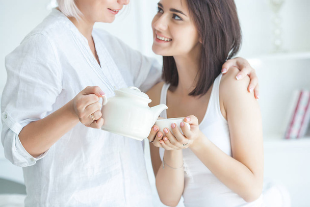 δύο γυναίκες να μιλούν. Μητέρα και κόρη μέσα μαζί. Οι κυρίες πίνουν τσάι. Δύο γυναίκες στο σπίτι. Ώριμη μητέρα και την ενήλικη κόρη της ασπαση.  - Φωτογραφία, εικόνα