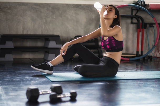 Chica de fitness cansado beber agua en el gimnasio
 - Foto, Imagen