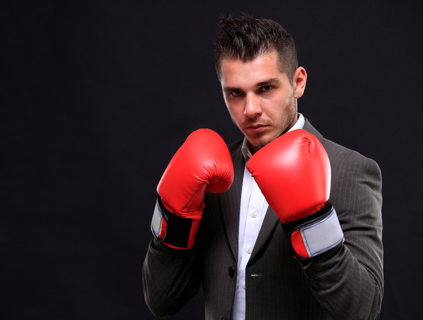 zakenman klaar om te vechten met bokshandschoenen - geïsoleerd op zwarte achtergrond - Foto, afbeelding