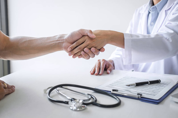 Professional female doctor in white coat shaking hand with patie - Photo, image