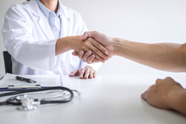 Professional female doctor in white coat shaking hand with patie - Zdjęcie, obraz