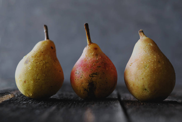 Juicy yellow pears with dark shadows at dark background - 写真・画像