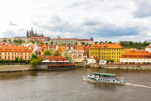 Prager Stadtbild mit Ausflugsschiff auf dem Fluss, Tschechische Republik. Europäische Stadt mit antiken architektonischen Gebäuden, berühmter Ort für Reisen und Tourismus - Foto, Bild