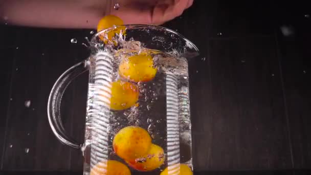 Splashing fruit on water. Apricots in slow motion fall into a vessel with water. Spectacular frame with fruits - Video