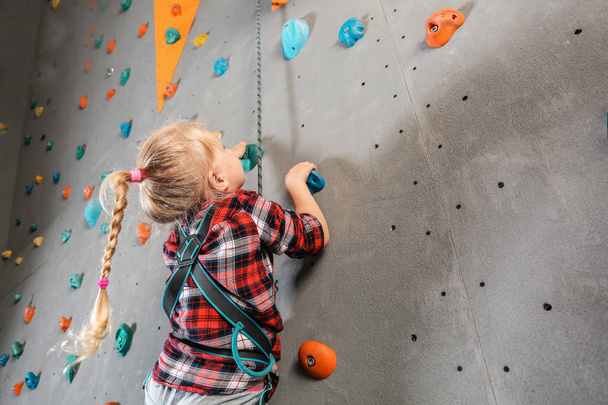 Little girl climbing wall in gym - Foto, imagen