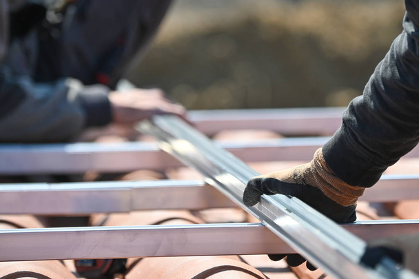 будівельники встановлюють металеву інфраструктуру для альтернативних енергетичних фотоелектричних сонячних панелей на даху
  - Фото, зображення