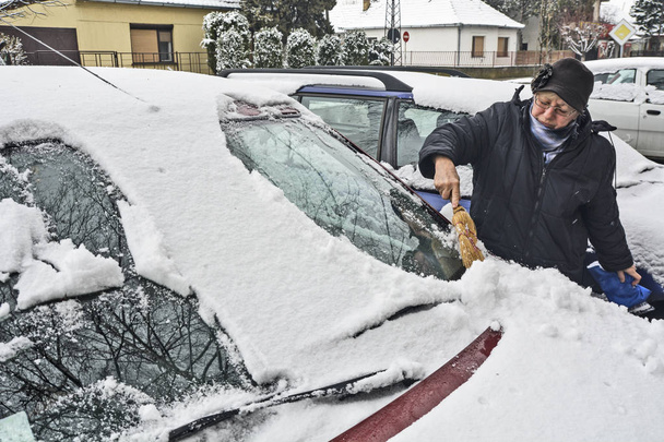 Ο οδηγός καθαρίζει το χιόνι από το παρμπρίζ  - Φωτογραφία, εικόνα