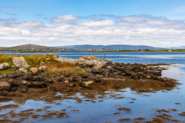 Bay with low tide, seaweeds, boat and mountains in Carraroe - Photo, Image