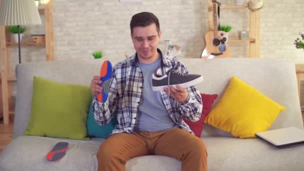 man sitting on the couch inserts orthopedic insoles in shoes - Video, Çekim