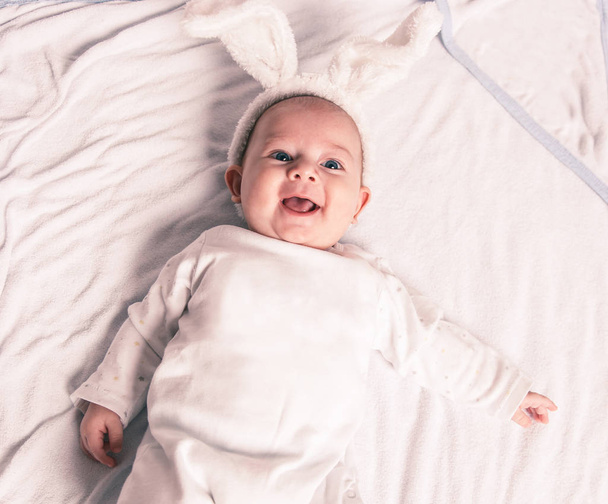 portrait of adorable smiling baby in Bunny suit lies in the crib - Foto, afbeelding
