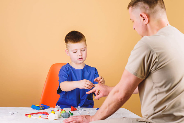 Medical examination. Hospital worker. Medical service. Analysis laboratory. Kid little doctor sit table medical tools. Health care. Pediatrician concept. Boy cute child and his father doctor - Foto, Bild