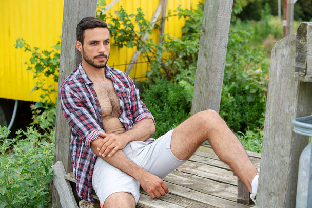 portrait of sexy man with open shirt sitting outdoors  - Zdjęcie, obraz