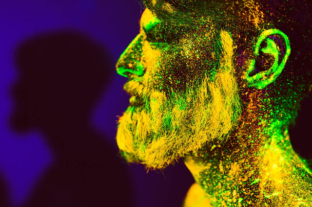 Concept. Portrait of a bearded man. The man is painted in ultraviolet powder - Φωτογραφία, εικόνα