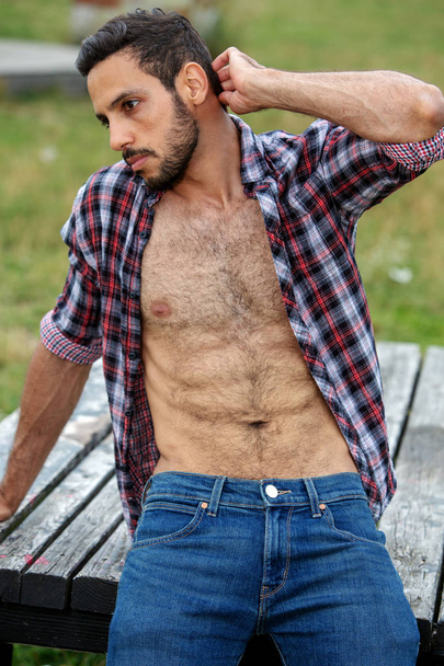 portrait of sexy man with open shirt sitting outdoors - Zdjęcie, obraz