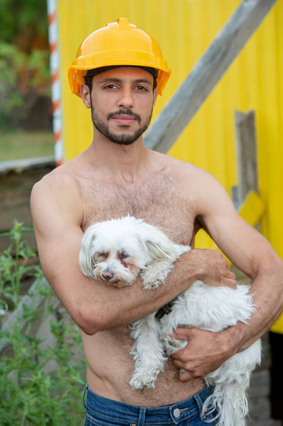 portrait of handsome shirtless man holding a white little dog - Foto, afbeelding