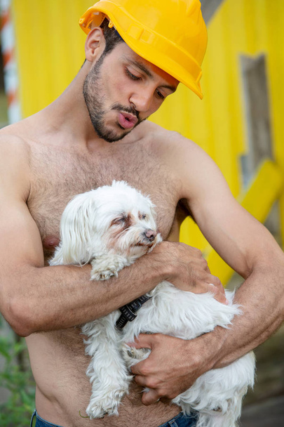 portrait of handsome shirtless man holding a white little dog - Fotó, kép