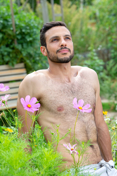 hombre guapo sin camisa con barba sentado fuera en el jardín
  - Foto, imagen
