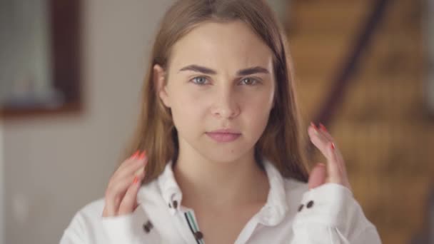 Portrait of pretty girl with heterochromia with headache massaging her head with fingers. Unusual girl with different eyes color at home. Concept of pain, migraine. Real people series. Real people. - Filmagem, Vídeo