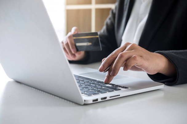 Geschäftsfrau hält Kreditkarte in der Hand und tippt auf Laptop - Foto, Bild
