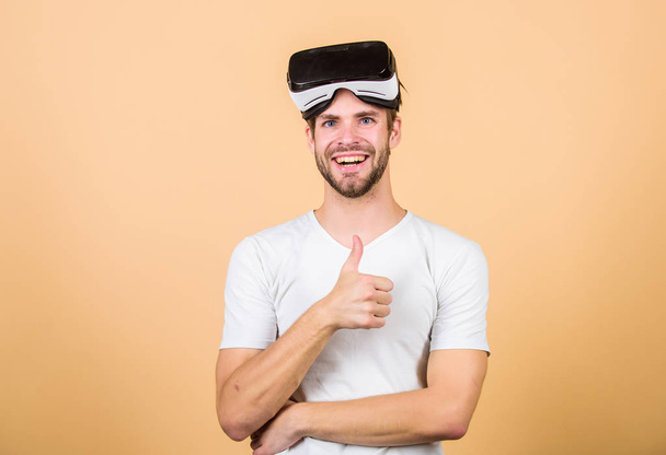 Entertainment and education. Virtual communication. Augmented 3D world. Virtual simulation. Man play game in VR glasses. Explore cyber space. Man hipster virtual reality headset on peach background - Foto, afbeelding