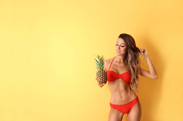 Pretty sexy woman in stylish bikini with pineapple on color background, space for text - Foto, Imagem