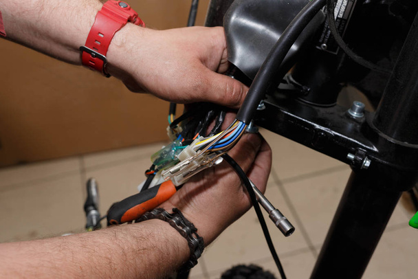 The process of connecting electrical wires in the assembly of a new motorcycle in operation. - Фото, изображение