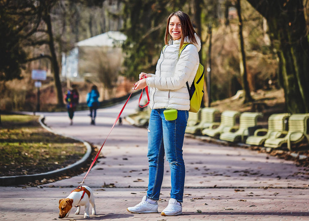 Genç şık hipster kadın parkta jack russell köpek yavrusu ile yürüyüş - Fotoğraf, Görsel