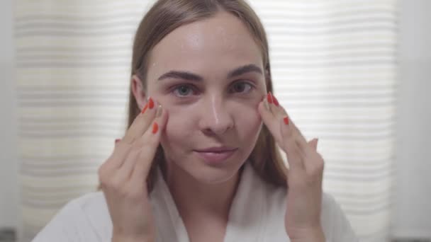 Beauty portrait of young woman with smooth healthy skin, she gently touches her face with her fingers. Cute girl with different colored eyes. Skincare and beauty concept. Real people series. - Кадры, видео