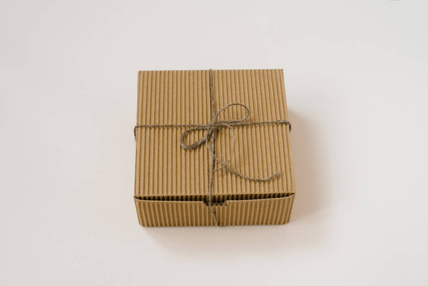 craft gift box tied with twine with on beige background. Gift wrap for birthday in natural style - Foto, Bild