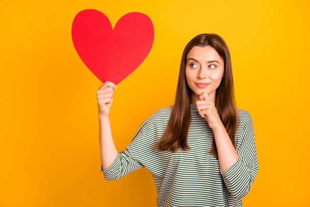 Photo of charming cute suspicious woman thinking on what guy of three ones she has will get this heart while isolated with yellow background - Fotó, kép