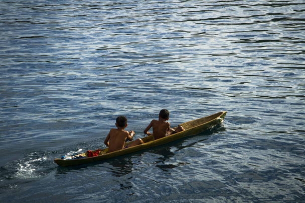 Local fisherman young boys play on the small traditional paddle boat - Photo, Image