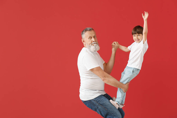 Cute little boy playing with grandfather on color background - Foto, afbeelding