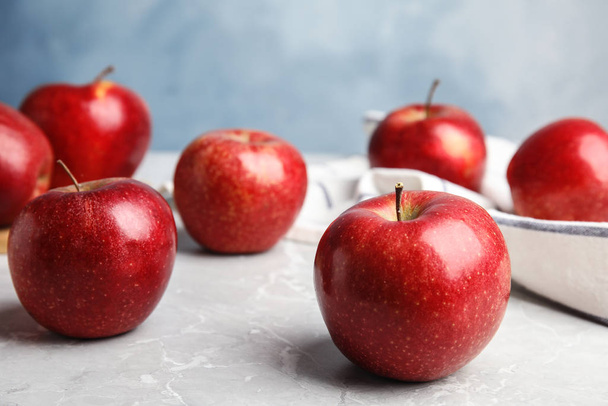 Ripe juicy red apples on grey table against blue background. Space for text - Foto, Imagen