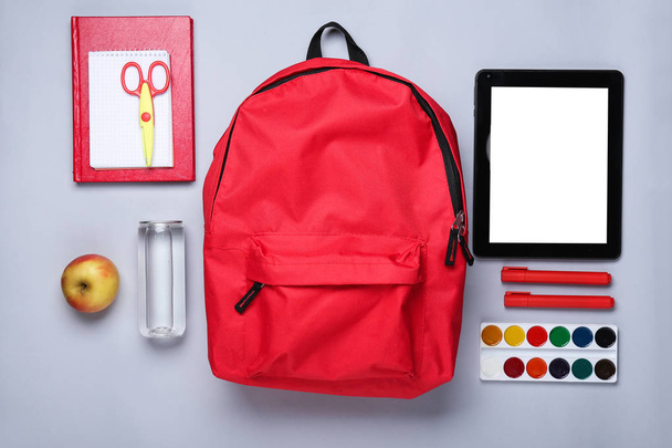 Plecak szkolny, tablet komputerowy i papeteria na jasnym tle - Zdjęcie, obraz